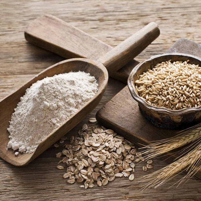 Whole grain and flour on wooden background close up