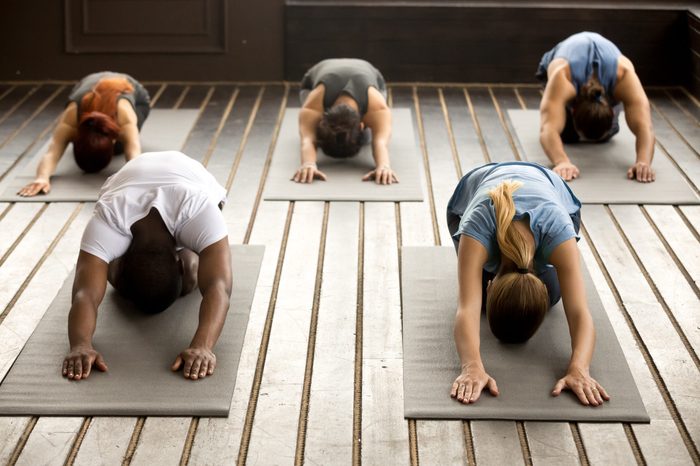 Group of young sporty afro american and caucasian people practicing yoga lesson stretching in Child exercise, Balasana pose, working out, indoor, studio. Healthy lifestyle concept