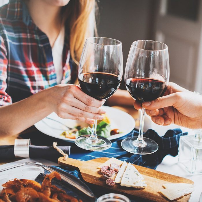 Young romantic couple celebrating with glasses of red wine