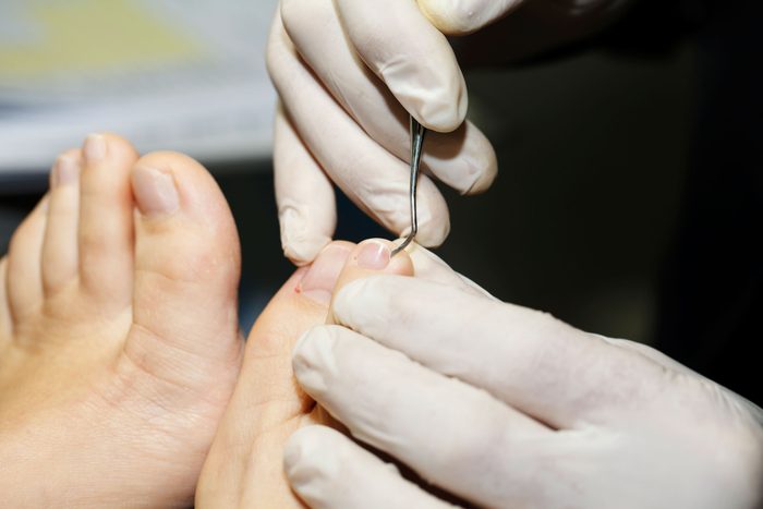 close up of person grooming another person's toenails