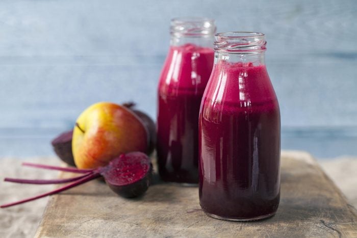 two bottles of beet juice on a cutting board with other fruit