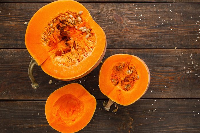 Set of orange pumpkins on wood flat lay free space. Fresh cut squashes on wooden table, country autumn background. Seasonal, harvest, fall, organic food, dieting, healthy food concept