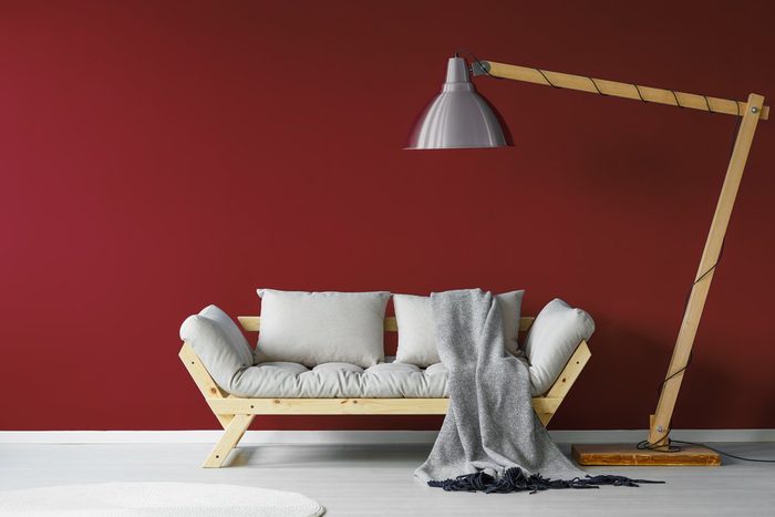 Comfortable couch with a large lamp standing over it in a minimalistic living room interior 