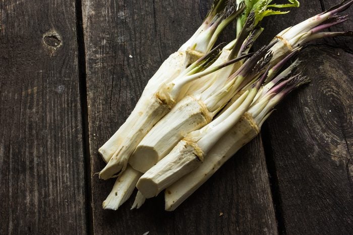 raw horseradish root with leaves on wooden background.
