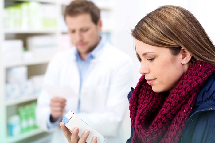 patient looking at Rx in pharmacy with pharmacist in background