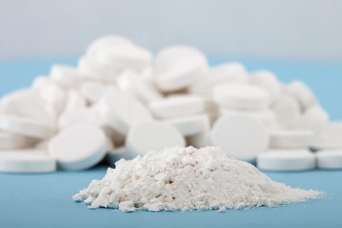 forefront of crushed pills on a blurred background of whole tablets