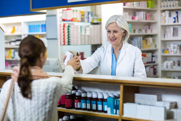 Pharmacist giving medicine box to customer in pharmacy