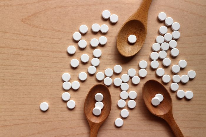 White round pills on wood spoons and medicines decorated on wood table