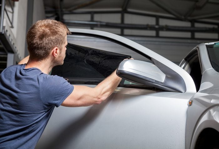 Applying tinting foil on a car window in a garage