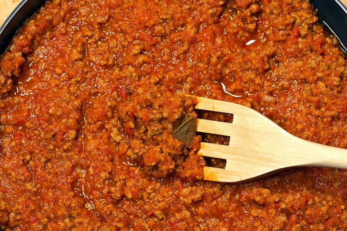 Detail of italian meat sauce (Bolognese or ragu) cooked with vegetables and tomato sauce and a wooden fork