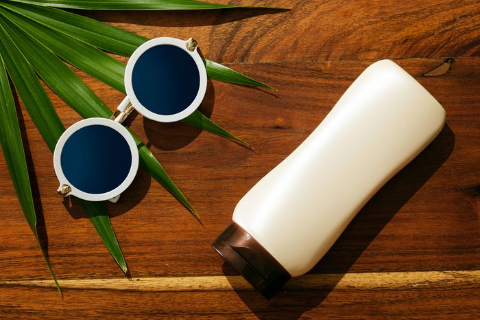 Different items for beach vacations. Sunscreen, sunglasses on wooden surface