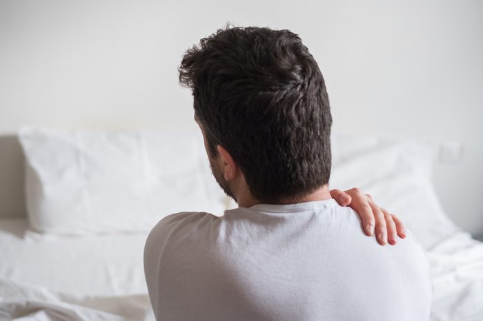 Wake up in the middle of the night | Rear view of one man sitting on bed having back pain