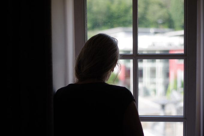 woman silhouette looking out of window of home