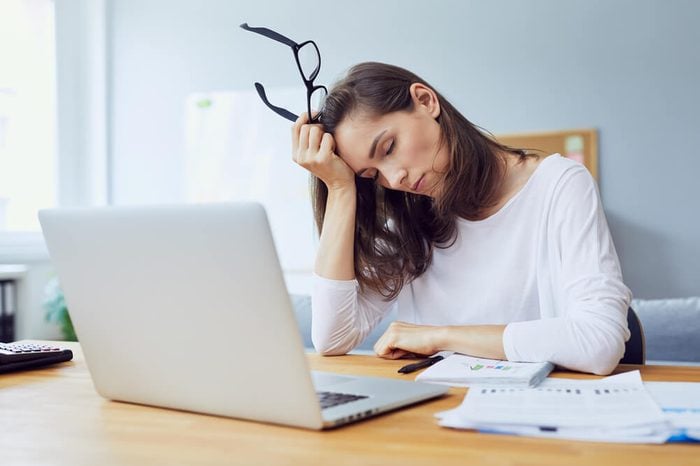 tired young office worker falling asleep at her desk while trying to work in modern office