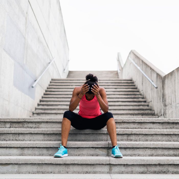 young woman sitting on stairs taking a break from workout