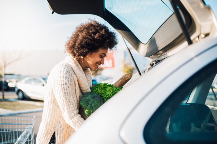 woman putting groceries into the trunk of car