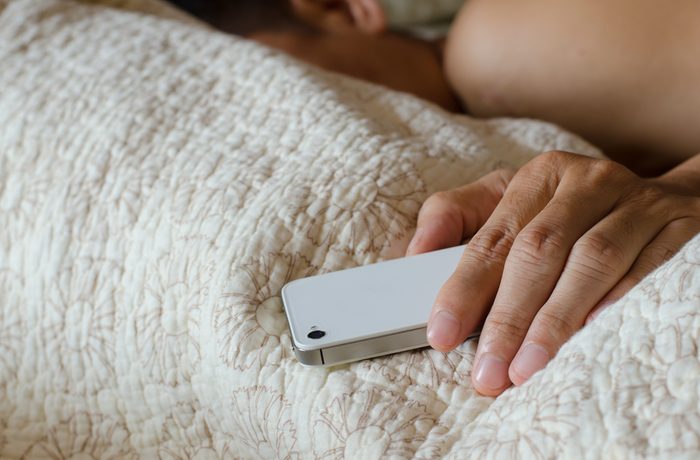 man sleeping in bed while holding his cellphone
