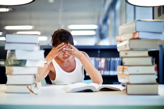frustrated woman in library with stack of books