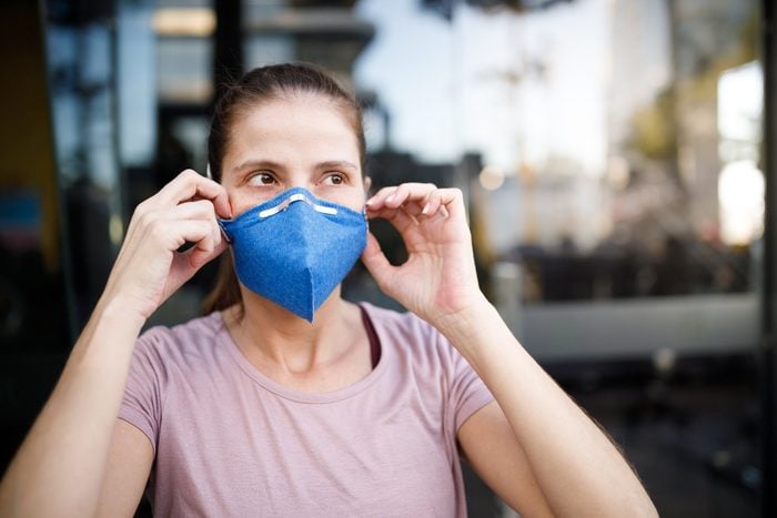 woman putting mask on face to protect from coronavirus