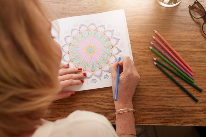 overhead shot of woman drawing in adult coloring book