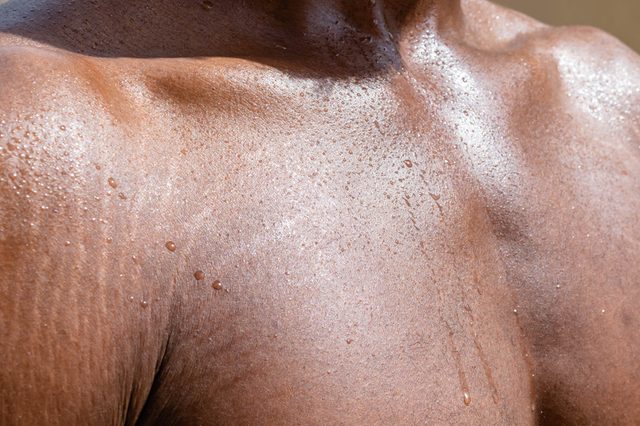 Close up of Black Male sweaty torso with stretchmarks Close up of sweat building up in a African mans body after hard work for summer hear concept