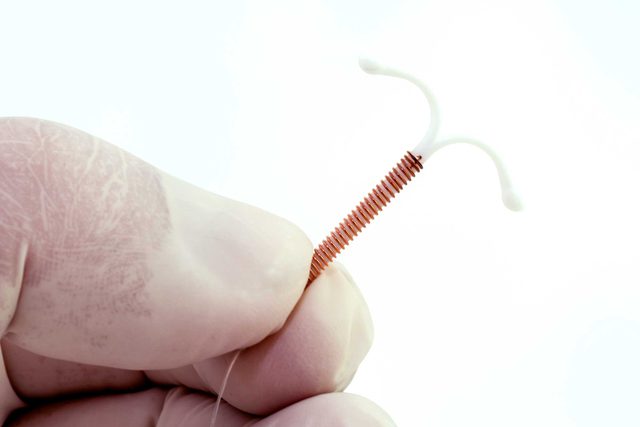 health myths gynecologists hear | gloved hand holding IUD