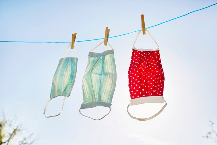 Still life of face masks hanging at clothesline against clear sky and sun, DIY sewing project