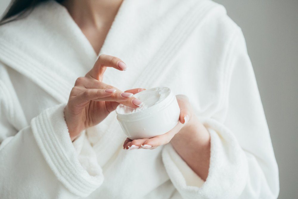 beauty products | Beautiful groomed woman's hands holding a cream jar on the fluffy blanket. Moisturizing cream for clean and soft skin in winter time. Manicure beauty salon. Healthcare concept. Spa