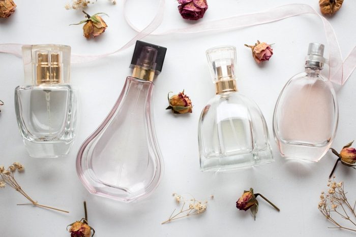 shouldn't be stored in the bathroom | bottle of woman perfume on white background with roses. gift.