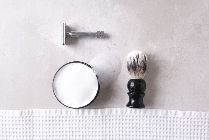 shouldn't be stored in the bathroom | Shaving Still Life: Safety razor with towel, brush and soap on a gray tile surface.