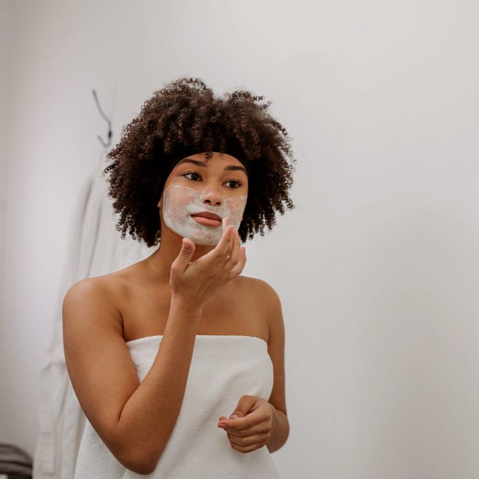 woman applying face mask on face in bathroom