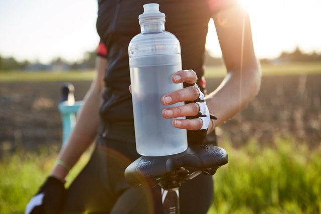 cause dehydration | close up of cyclist holding water bottle