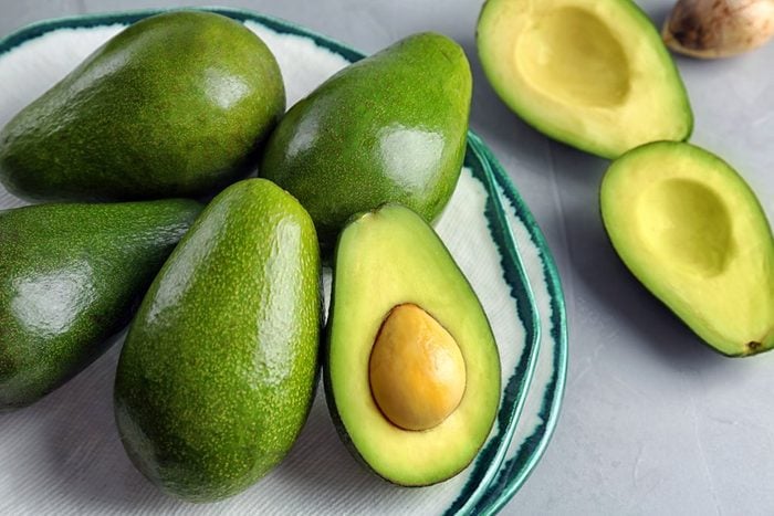 Plate with ripe avocados on grey table | foods to avoid before workout