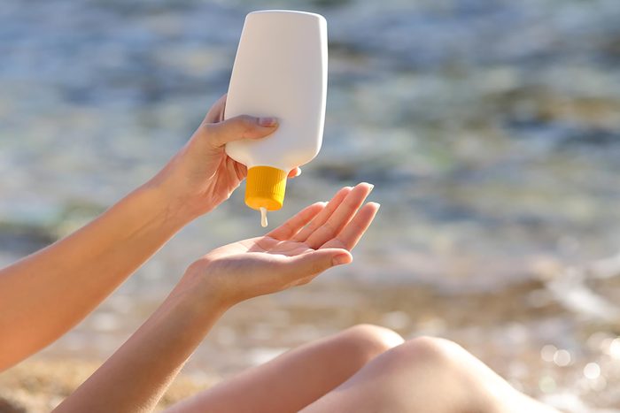 woman squeezing sunscreen into hand at the beach