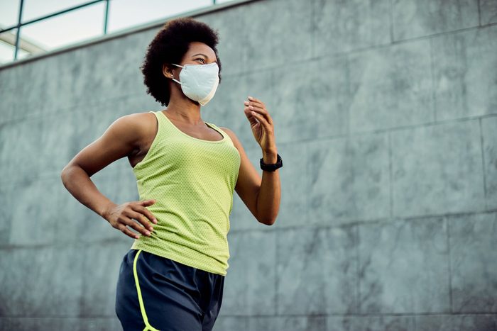young woman running outside with face mask on