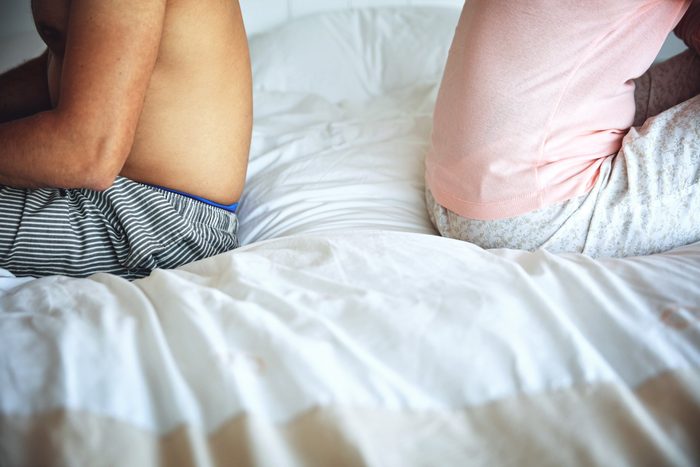 signs your body is in trouble | couple sitting back to back in bed