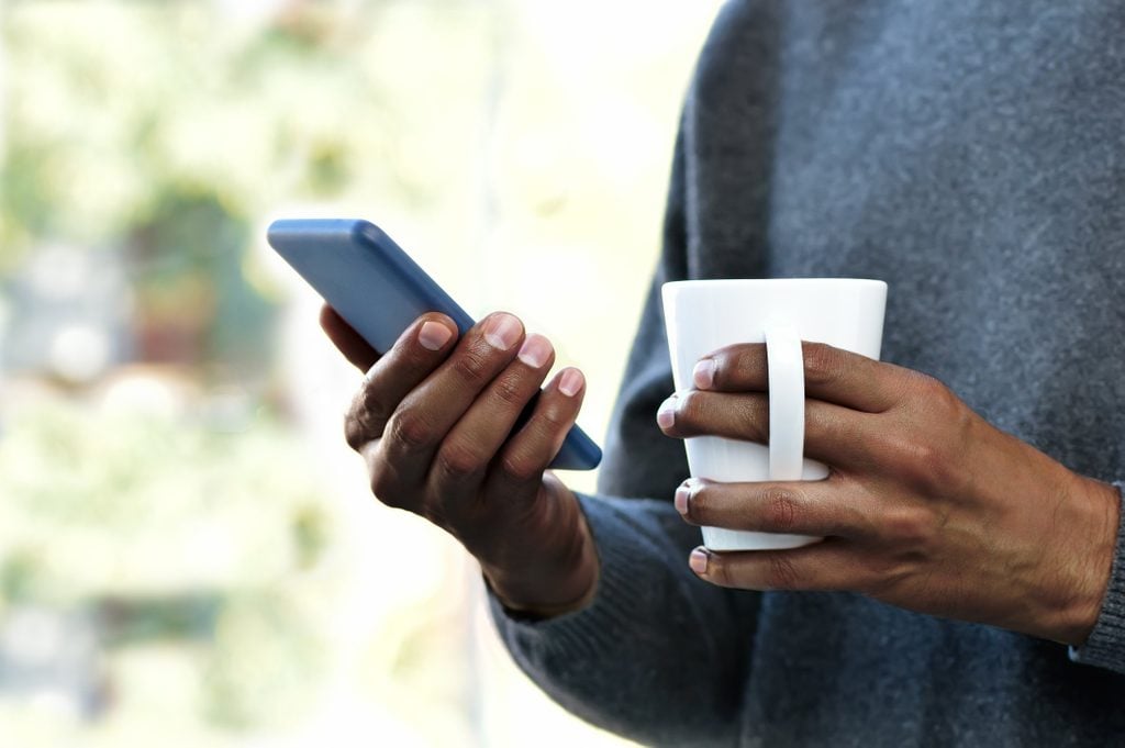 nomophobia | close up of person holding coffee mug and smartphone