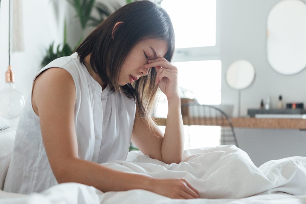 period flu | Young Woman Suffering Headache In Bed
