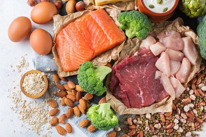 Assortment of healthy protein source and body building food. Meat beef salmon chicken breast eggs dairy products cheese yogurt beans artichokes broccoli nuts oat meal. Top view