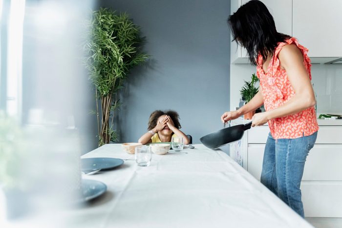 disordered eating triggers kids | Mother serving meal for daughter sitting at dining table