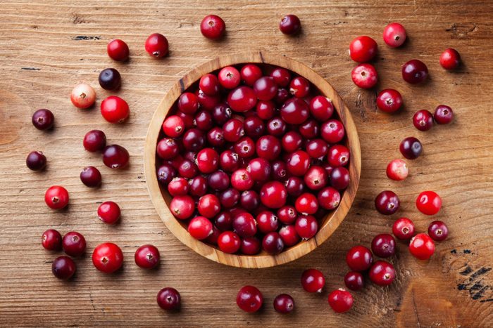 cranberry health benefits | Fresh raw cranberry in wooden bowl on rustic table top view.