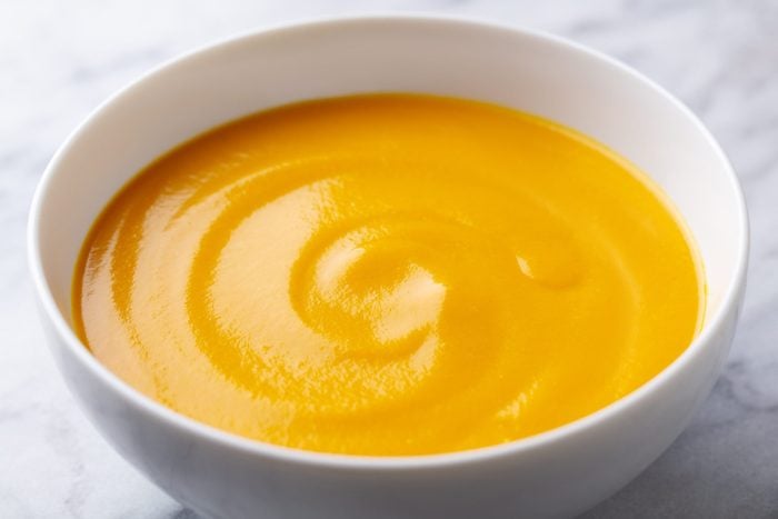 Healthy comfort pumpkin, butternut squash soup in white bowl. Marble background. Close up.