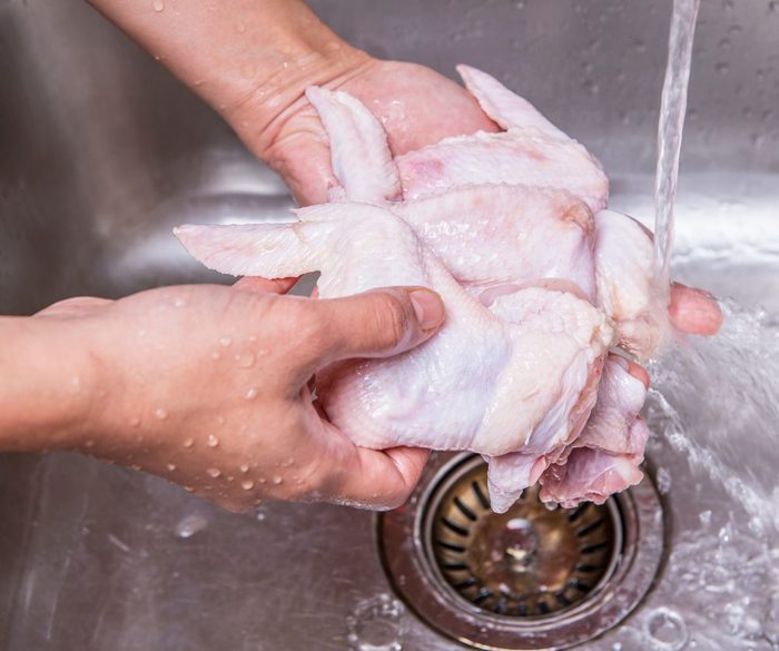washing chicken | Female hands washing and cleaning chicken wings at the kitchen sink