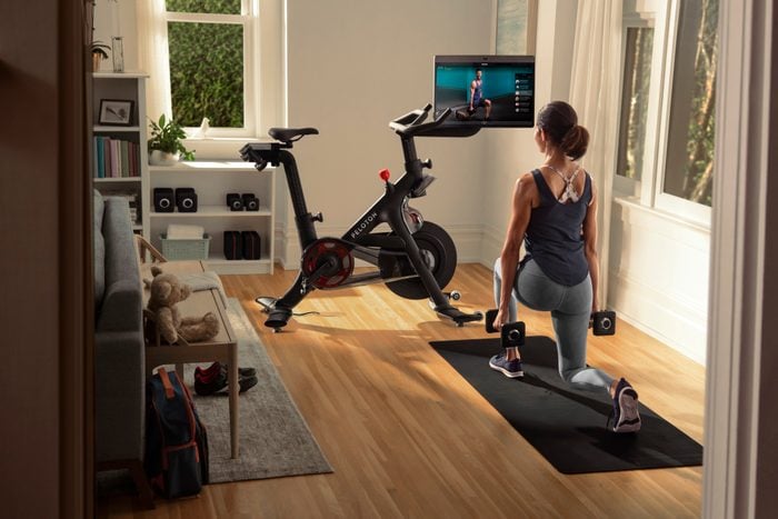 peleton bike+ review canada | image of the peleton with woman doing floor exercises next to it