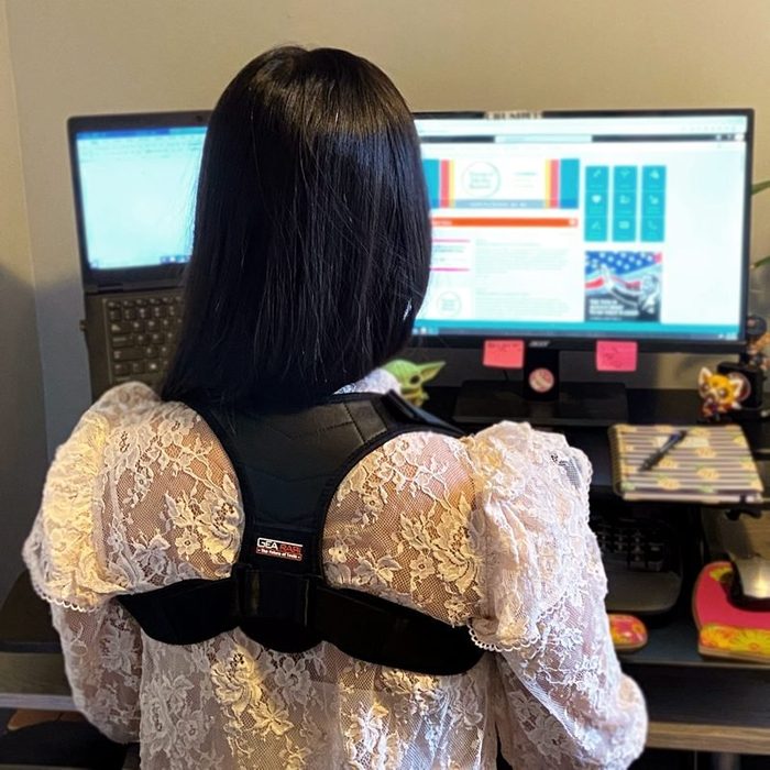 Back Posture Corrector | woman wearing back posture corrector sitting in front of a computer