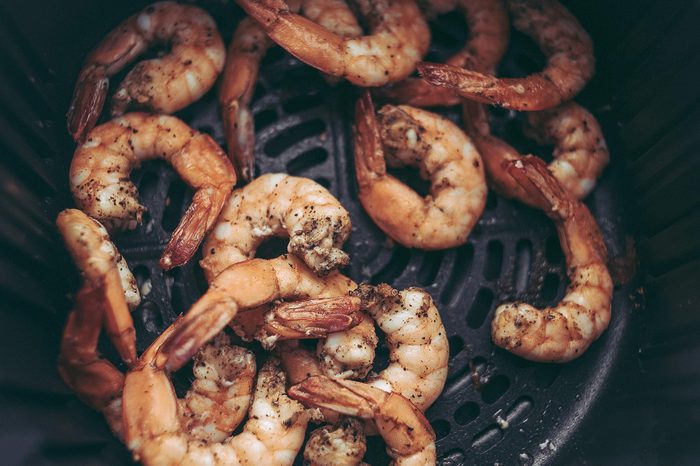 Roasted shrimps with garlic and herbs. Seafood, shelfish. Shrimps Prawns grilled with spices and garlic on black stone background, copy space. Shrimps prawns on cast iron pan.