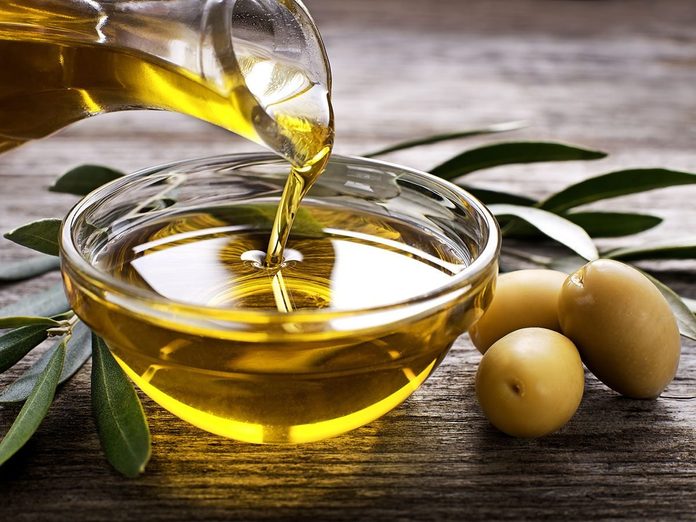 Bottle pouring virgin olive oil in a bowl.