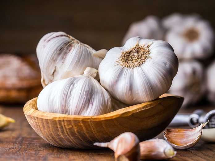 Garlic cloves and bulb in vintage wooden bowl.