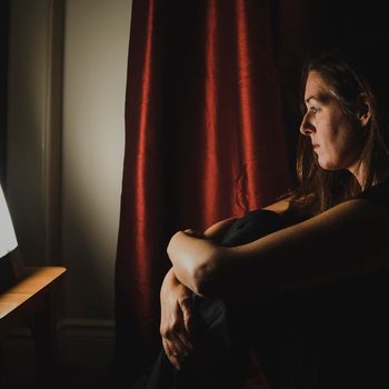 light therapy | Profile Of Woman Sitting Looking At Light Therapy Lamp In A Dark Room