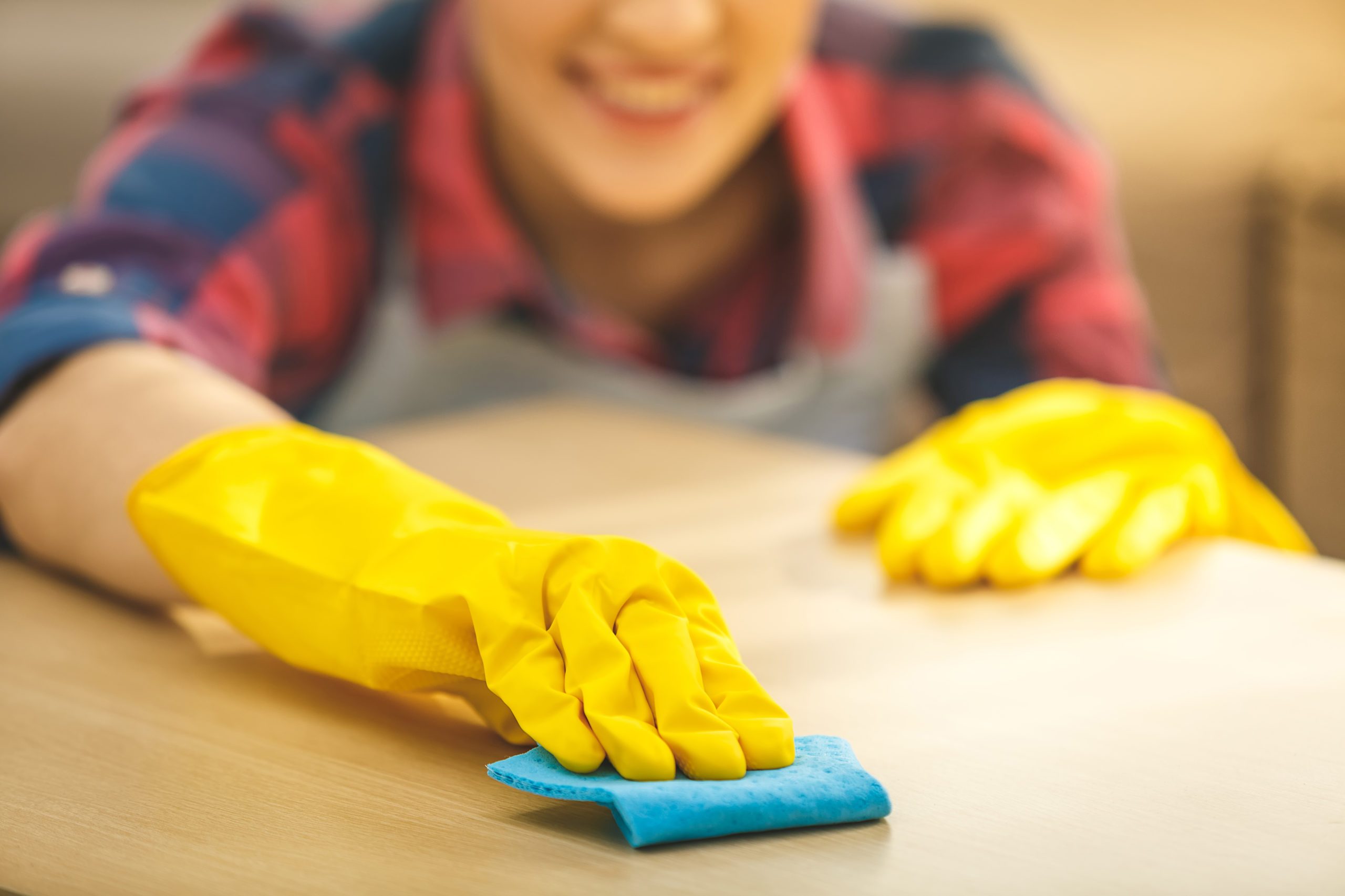 Woman,in,protective,gloves,is,smiling,and,wiping,dust,using